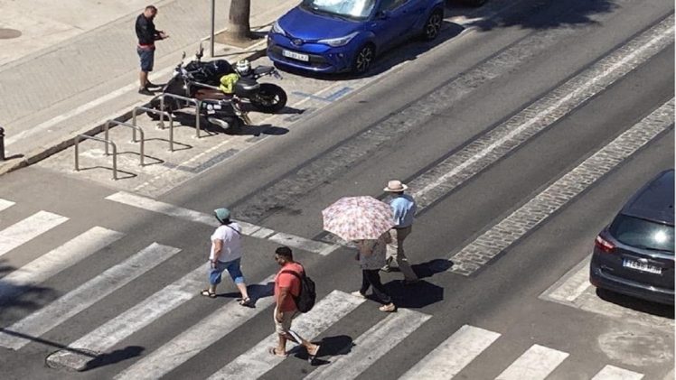 Turistas se protegen del calor durante su paseo por la ciudad.