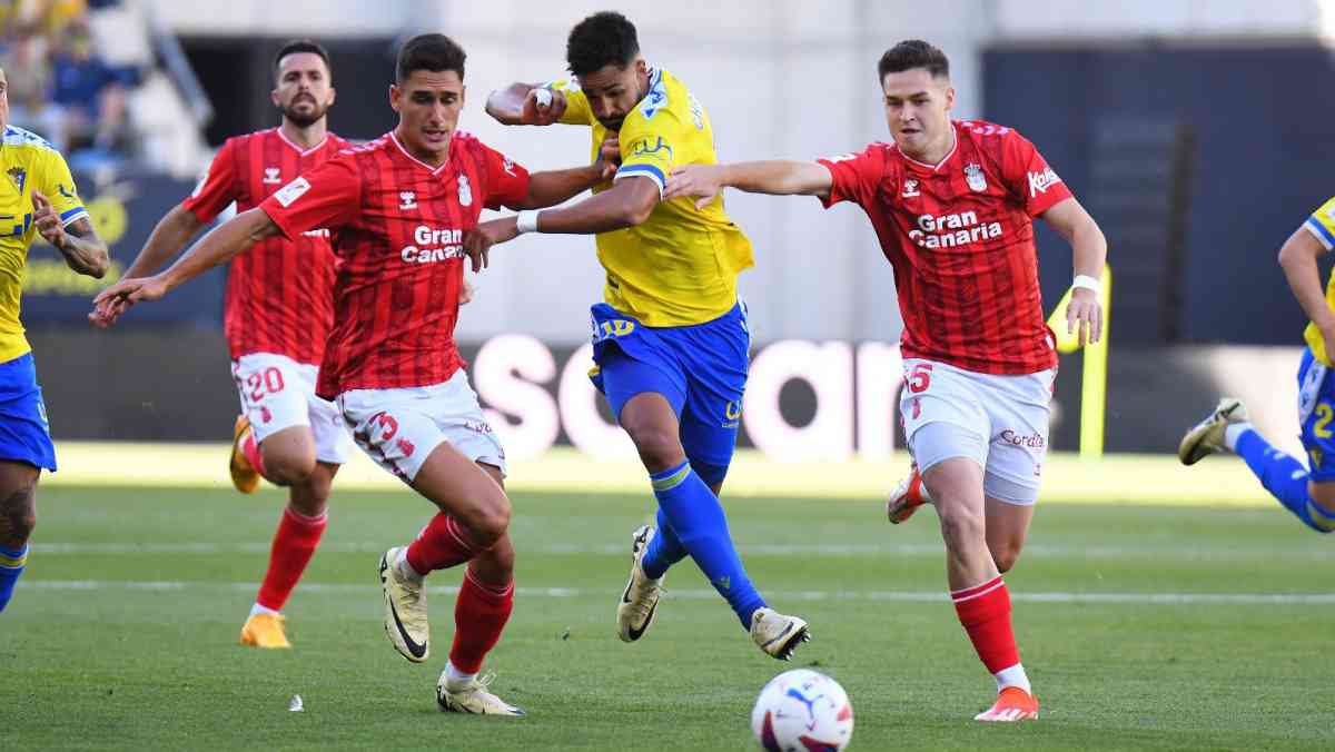 Chris Ramos forcejea con dos jugadores de Las Palmas.