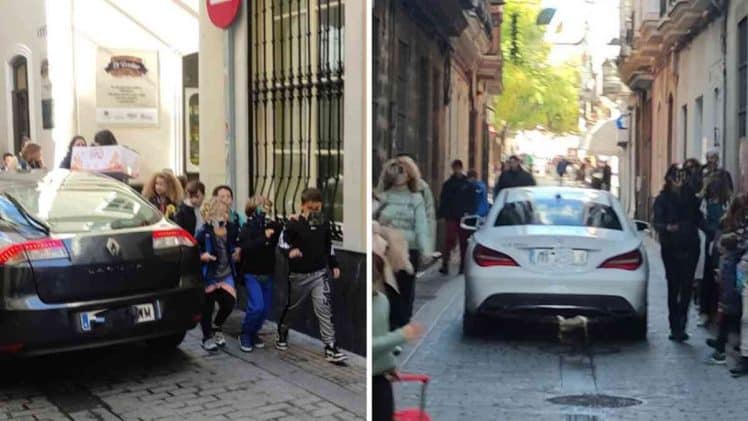 Vehículos pasando junto a los niños a su salida del colegio.